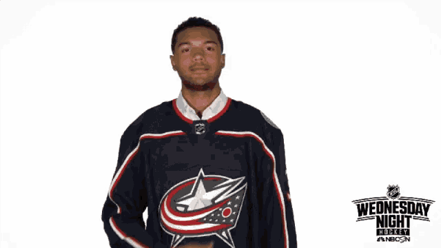 a hockey player applauds in front of a sign that says wednesday night