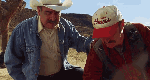 a man wearing an atlanta hawks hat is talking to another man