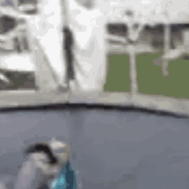 a blurry picture of a person jumping on a trampoline with a white tent in the background .