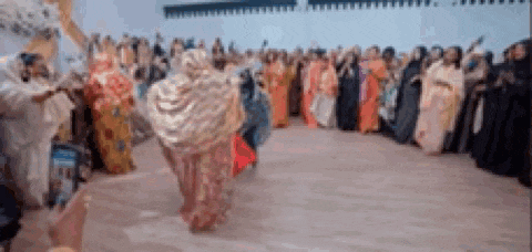 a large group of people are dancing in a circle on a dance floor .