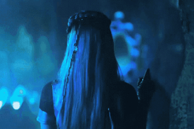 a woman with long blue hair is holding a black object