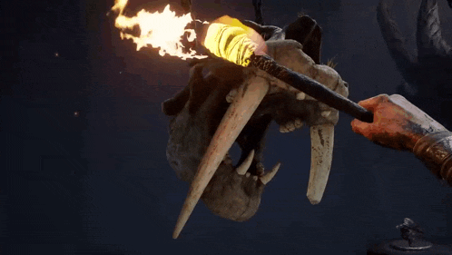a person is holding a torch in front of a skull with tusks