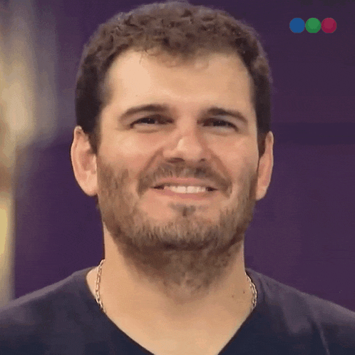 a man with a beard and a chain around his neck is smiling