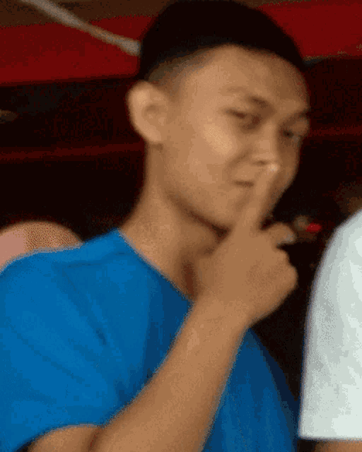 a man in a blue shirt is covering his mouth with his hand
