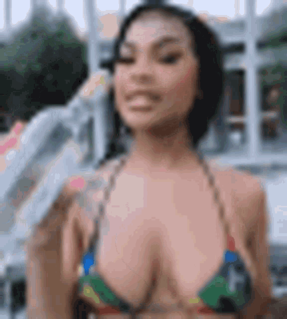 a woman in a bikini with a tattoo on her arm is standing in front of a building .