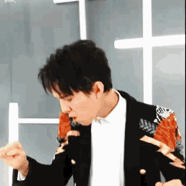 a man in a black jacket is eating something with a fork .