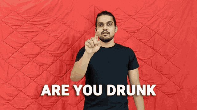 a man in a black shirt is making a hand gesture in front of a red background that says " are you drunk "