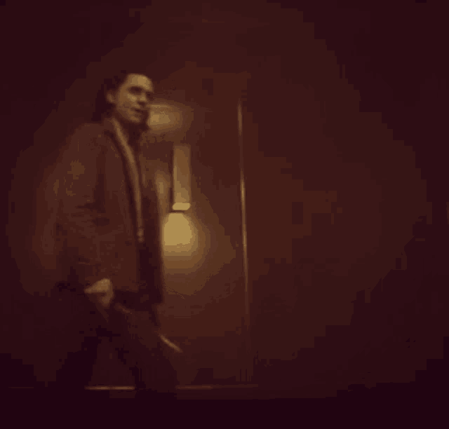 a man in a suit and tie stands in front of a dark wall