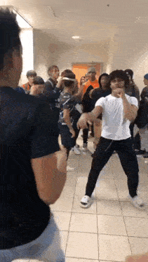 a group of young people are standing in a hallway dancing .