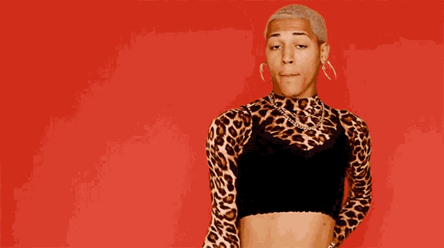 a man wearing a leopard print top and earrings