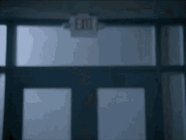 a close up of a man 's face in a dark room with a door in the background .