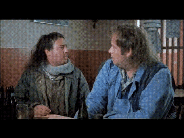 two men are sitting at a table and talking