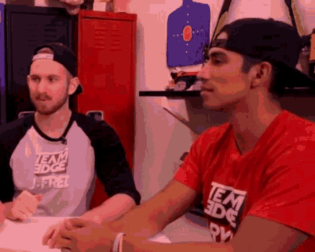 two men are sitting at a table talking to each other .