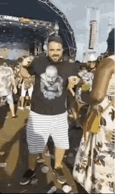 a man is standing in front of a crowd at a music festival holding a drink .