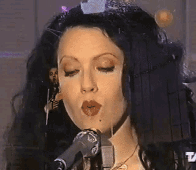 a woman singing into a microphone with the letter t on the bottom