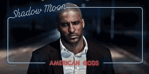 a man in a suit stands in front of a sign that says shadow moon