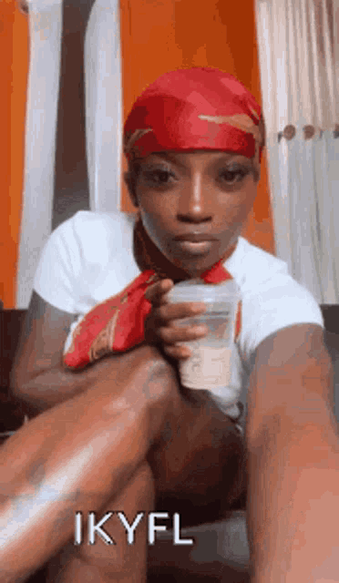 a woman is sitting on a couch holding a cup of coffee and wearing a red headband .