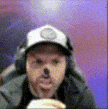 a man wearing a hat and headphones is eating a sandwich