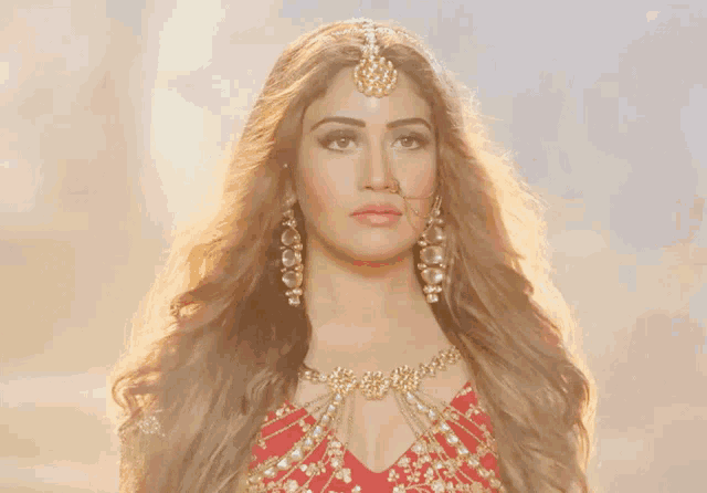 a woman wearing a red dress and gold jewelry