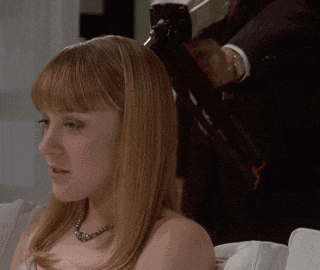 a woman sitting on a couch with a man holding a gun in the background