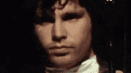 a close up of a man 's face in a dark room with a white shirt on .