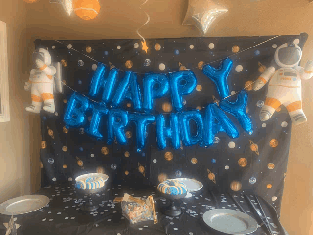 a happy birthday banner hangs over a table with plates