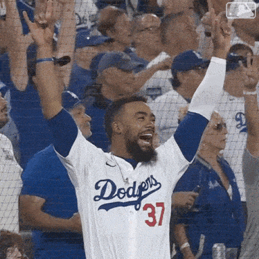 a man wearing a dodgers jersey celebrates in front of a crowd