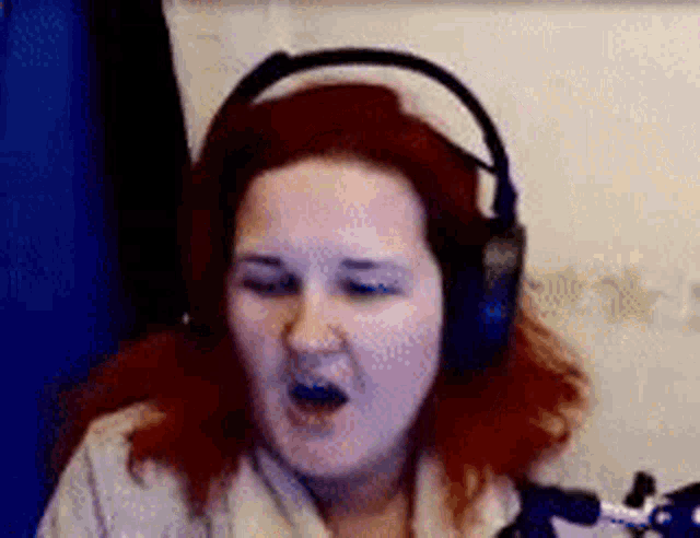 a woman with red hair is wearing headphones and making a funny face .