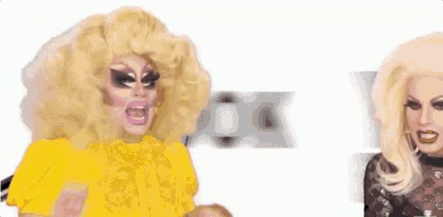 two drag queens are standing next to each other in front of a sign that says yes bitch