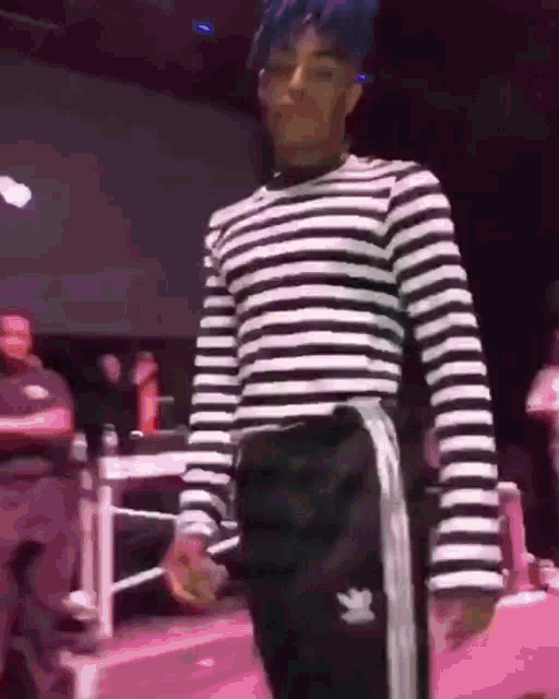 a man wearing a black and white striped shirt and black pants is standing on a stage .