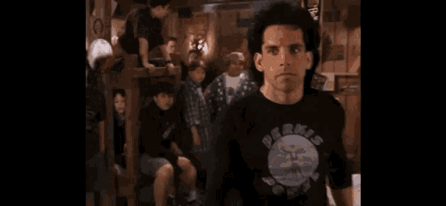 a man wearing a perks shirt is laughing in front of a group of people