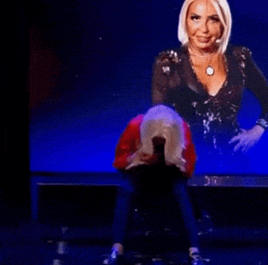 a woman in a black top is sitting on a stage with her head down