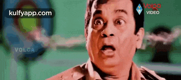 a man with a surprised look on his face is standing in front of a green background .