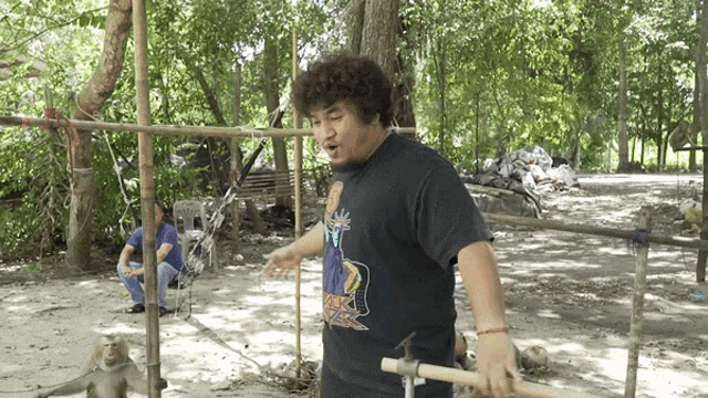 a man wearing a black shirt with a monkey on it holds a wooden stick