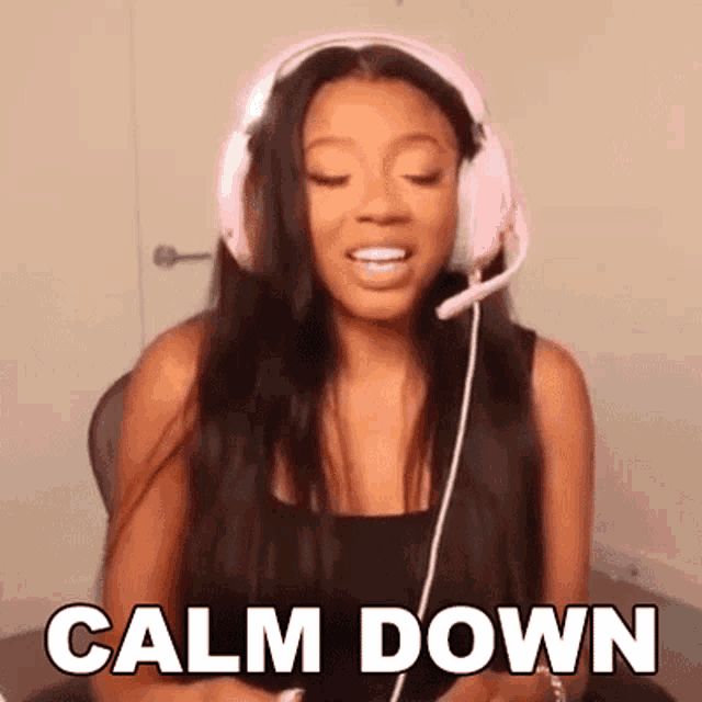 a woman wearing pink headphones and a microphone is making a calm down gesture .