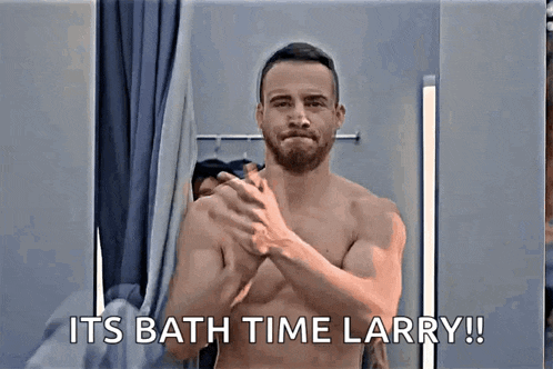 a shirtless man is washing his hands in front of a mirror and says " it 's bath time larry ! "