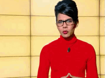 a woman wearing glasses and a red sweater stands in front of a popcorn time sign