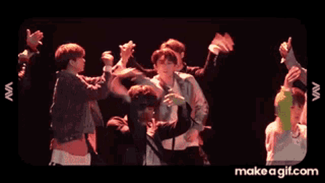 a group of young men are dancing on a stage in front of a camera .