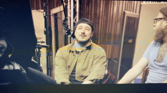 a man wearing a hat and glasses is sitting in a dark room