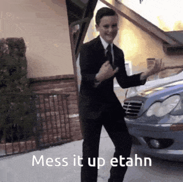 a man in a suit and tie is dancing in front of a car with the caption mess it up etahn .