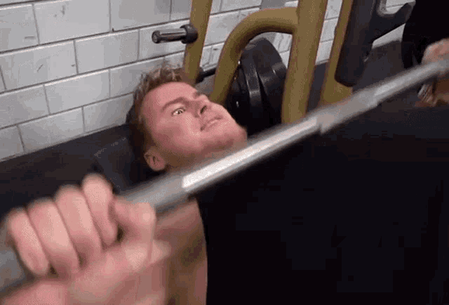 a man is sitting on a bench lifting a barbell .