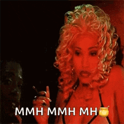 a woman with blonde curly hair is smoking a cigarette and says mmh mmh mmh