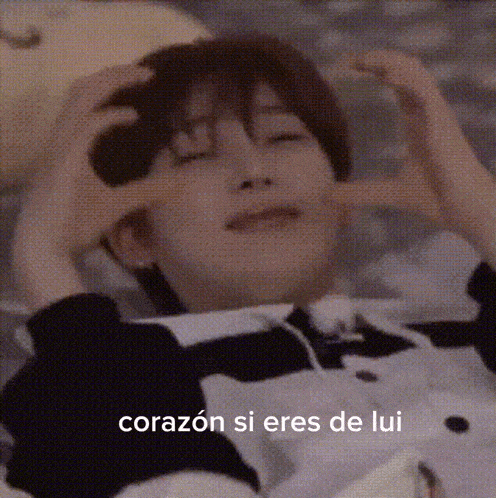 a person is laying down with their eyes closed and making a heart shape with their hands ..