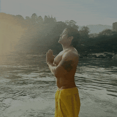 a poster for yash birla shows a shirtless man praying in front of a river