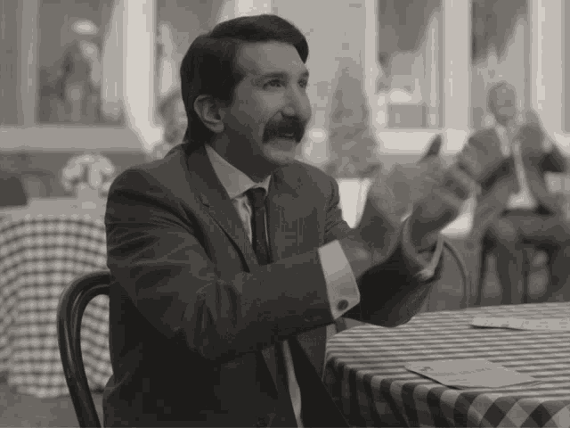 a man sitting at a table with his hands in the air