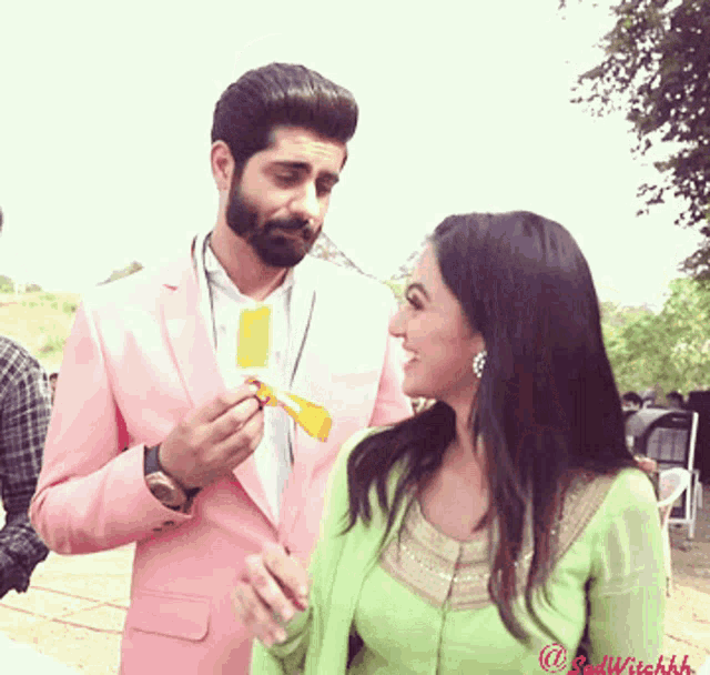 a man in a pink suit is feeding a woman an ice cream
