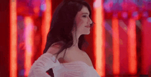 a woman in a white dress is standing in front of red lights .