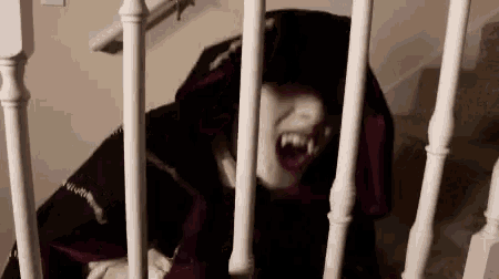 a person in a vampire costume is behind a railing on a set of stairs