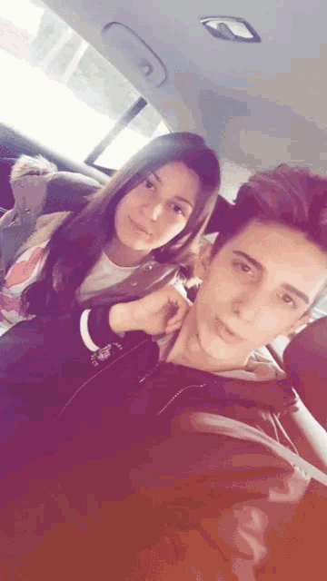 a boy and a girl are posing for a picture in the back of a car