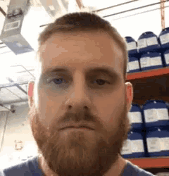 a man with a beard is making a funny face in front of a shelf of chemicals .